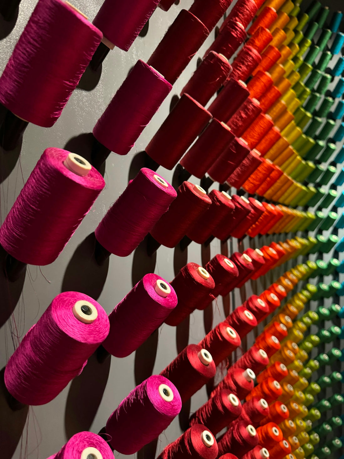 Many spools of thread are lined up on a wall