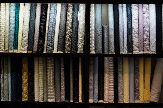 Shelves of rolled fabric with various patterns.